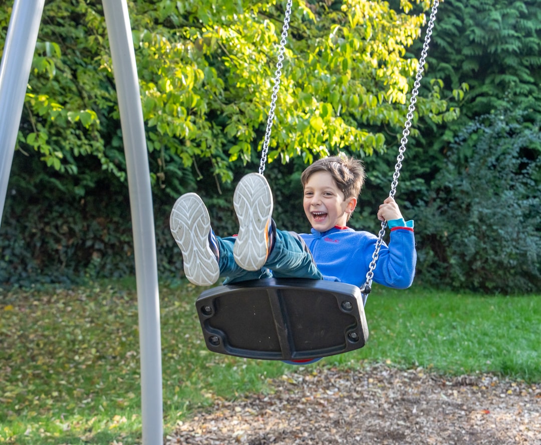 A happy boy swinging on a playground swing.