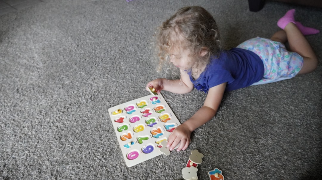 Toddler playing with alphabet puzzle on carpet